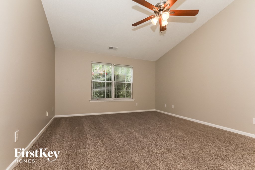 A room with a ceiling fan and a window with blinds.
