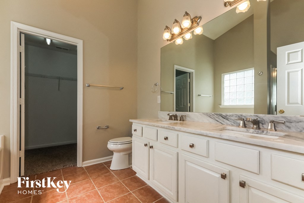 A bathroom with a toilet, sink, and mirror.