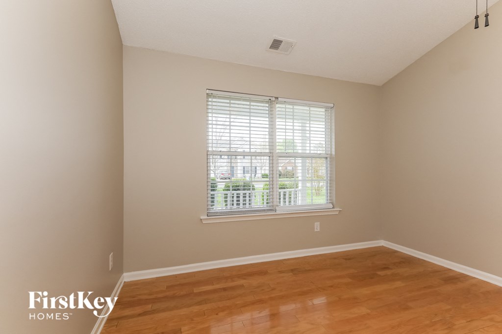 A room with wooden floors and a window with blinds.