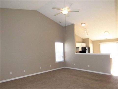 an empty living room with a ceiling fan
