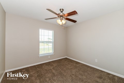 a living room with carpet and a ceiling fan