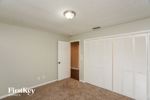 a bedroom with white closet doors and a door to a hallway