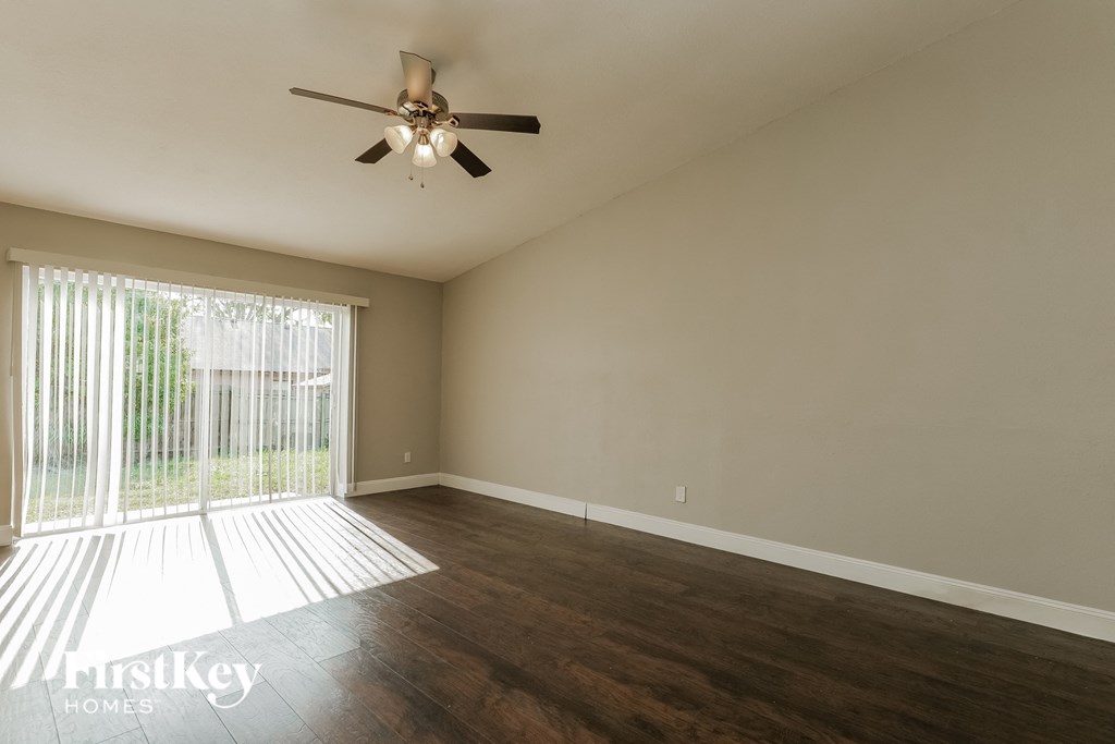 A room with a ceiling fan and sliding glass doors.
