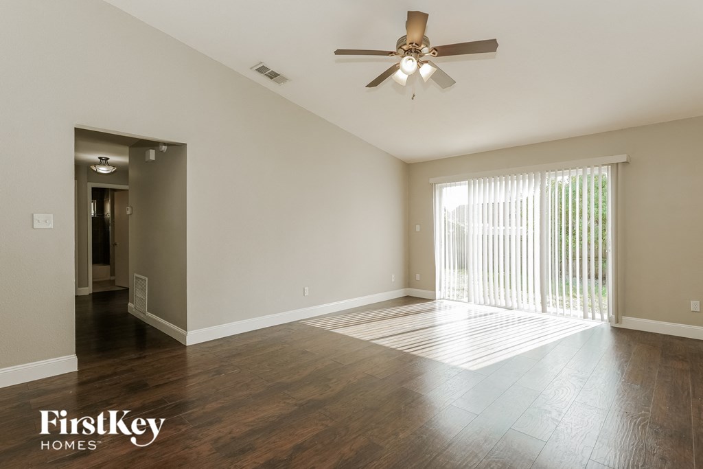 A spacious room with a ceiling fan and wooden flooring.