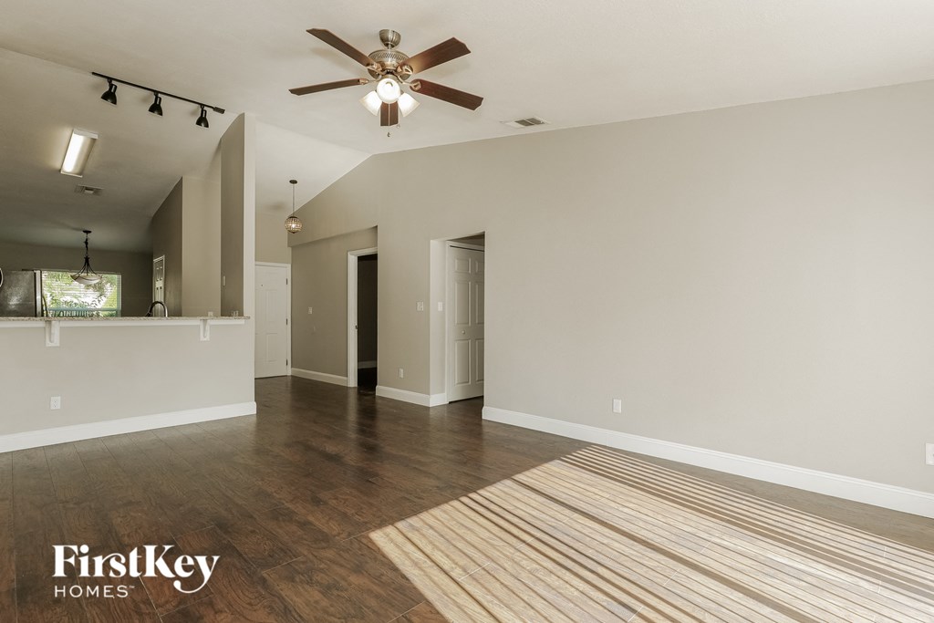 A spacious room with a ceiling fan and wooden flooring.