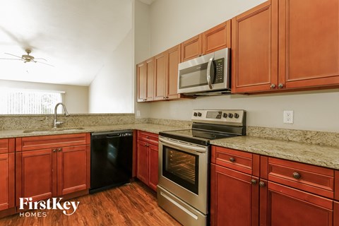 A kitchen with red cabinets and a stainless steel oven.