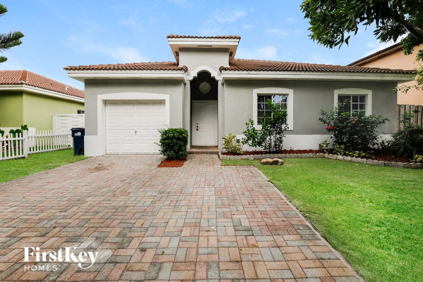 A house with a brick driveway and a garage door.