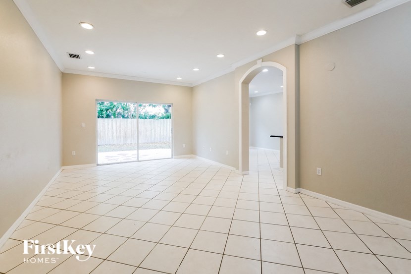 A spacious room with white tiled flooring and a large window.