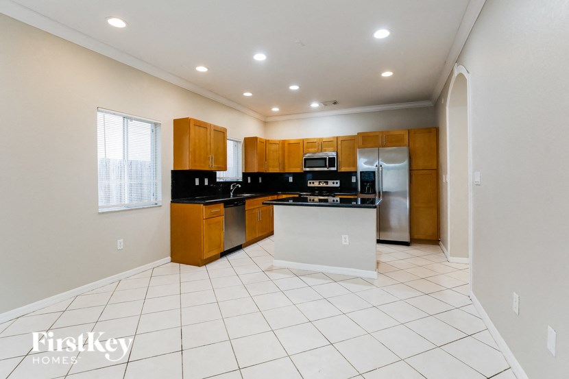 A kitchen with wooden cabinets and a white island.
