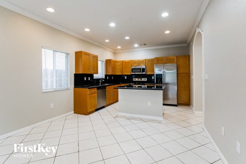 A kitchen with wooden cabinets and a white island.