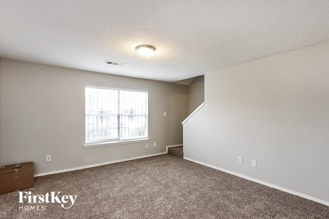 a spacious living room with carpet and a window