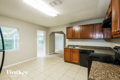 A kitchen with a black stove top oven and brown cabinets.
