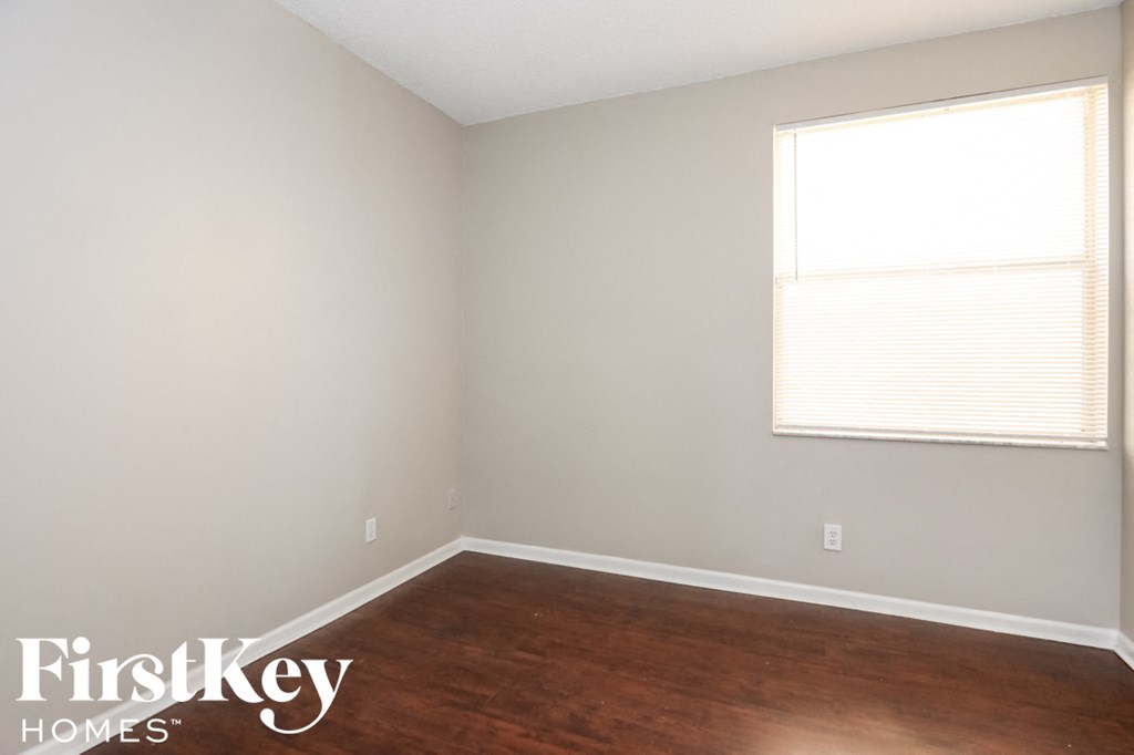 a room with wood floors and a window and white walls