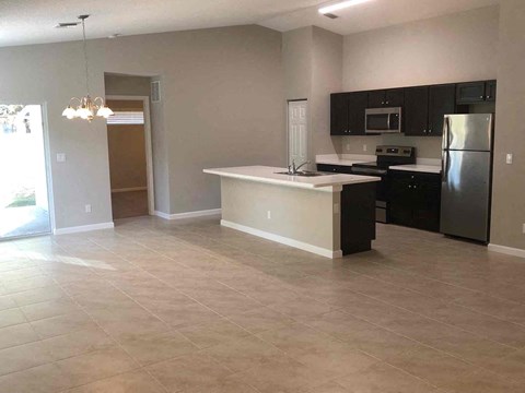 A kitchen with black cabinets and a white island.