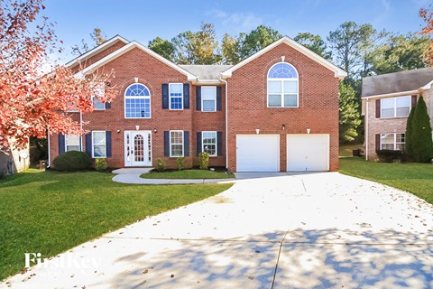 a large brick house with a white driveway in front of it