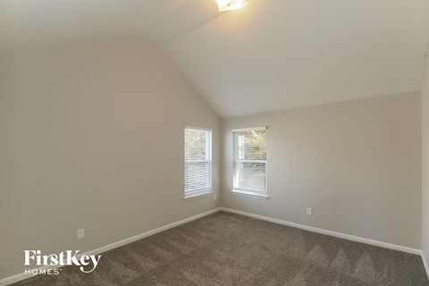 the living room of a house with carpet and two windows