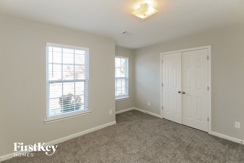 a bedroom with carpet and a white door and window