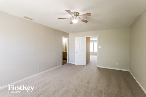 a spacious living room with carpet and a ceiling fan
