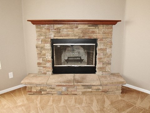 a stone fireplace in a living room with wood floors