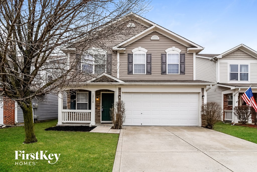 A house with a garage and a tree in front of it.