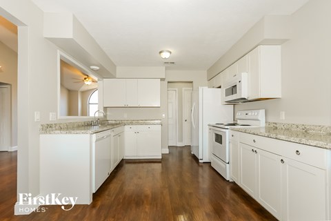 A kitchen with white cabinets and a wooden floor.