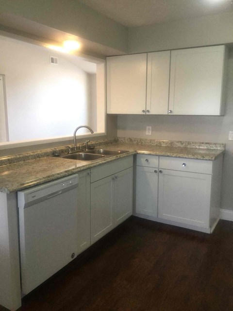 A kitchen with white cabinets and a granite countertop.