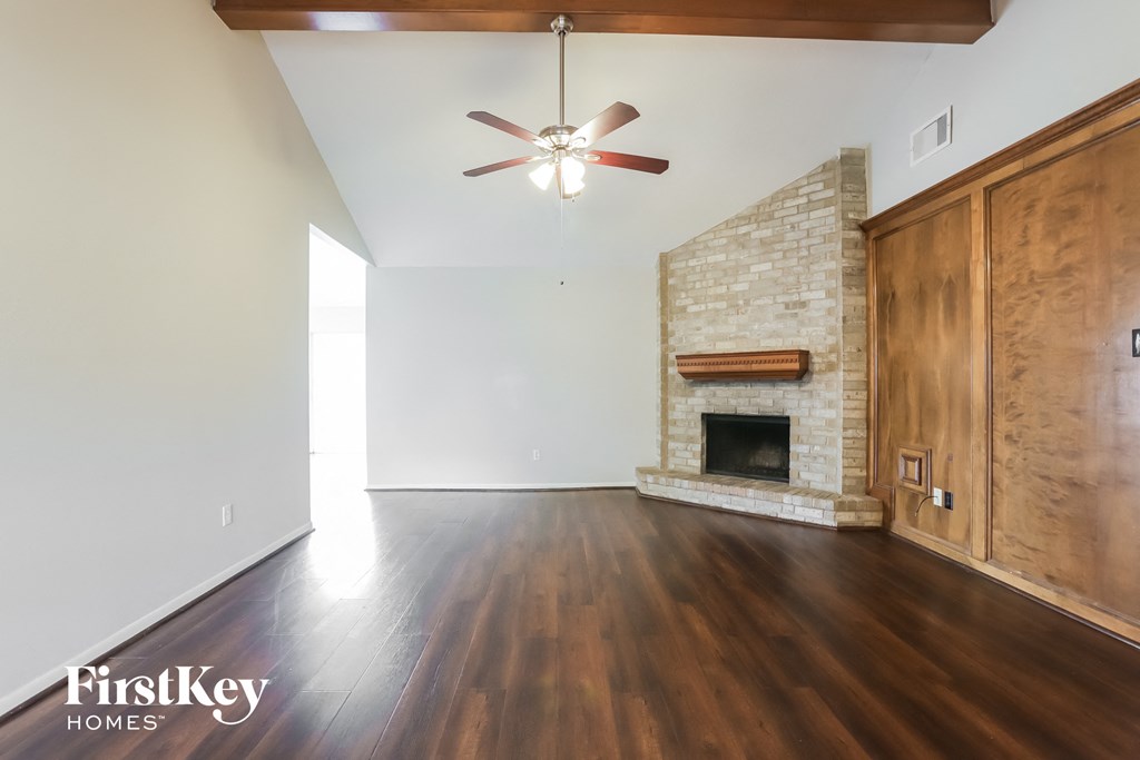 an empty living room with wood floors and a fireplace