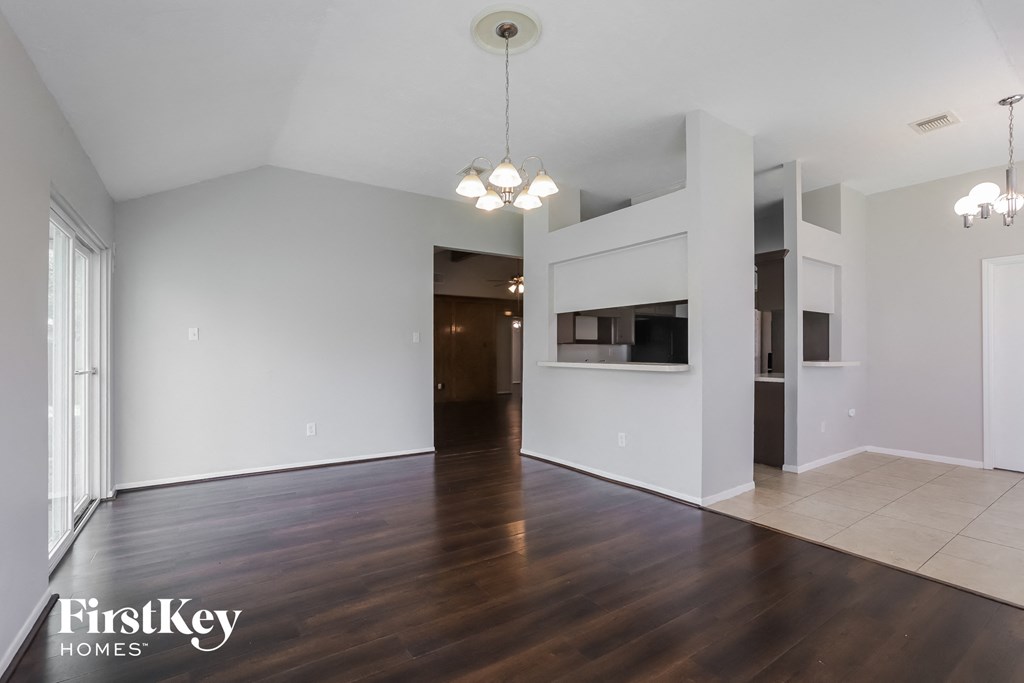the living room and dining room with wood flooring and white walls