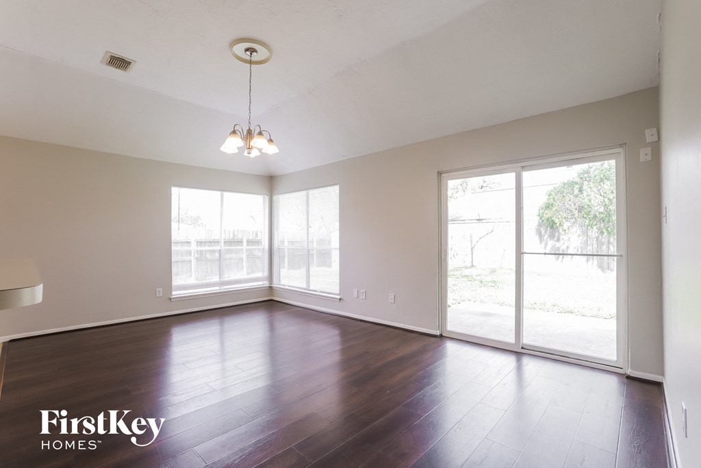 an empty living room with wood floors and large windows