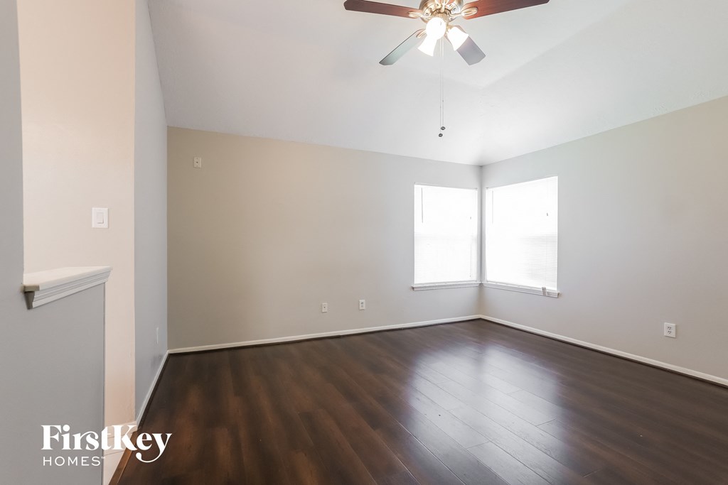 an empty living room with wood floors and a ceiling fan