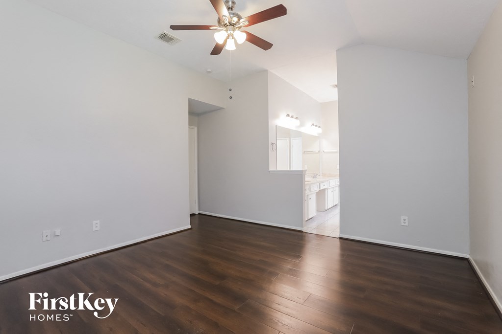 an empty living room with white walls and a ceiling fan