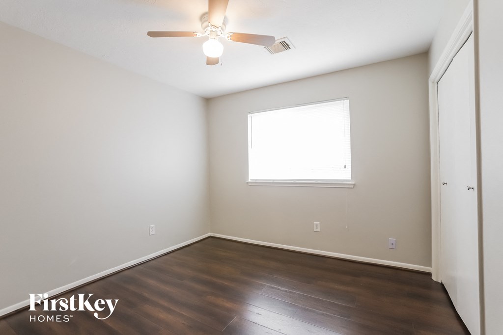 a bedroom with wood flooring and a ceiling fan