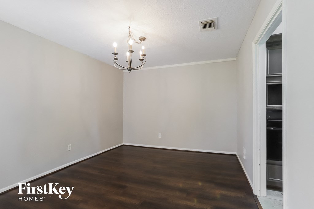a empty living room with wood flooring and a chandelier