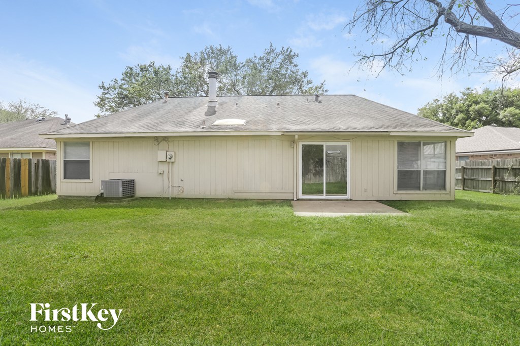 the backyard of a white house with a lawn and a fence