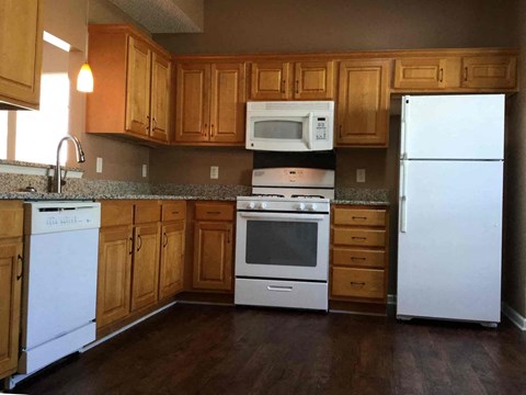 A kitchen with white appliances and wooden cabinets.