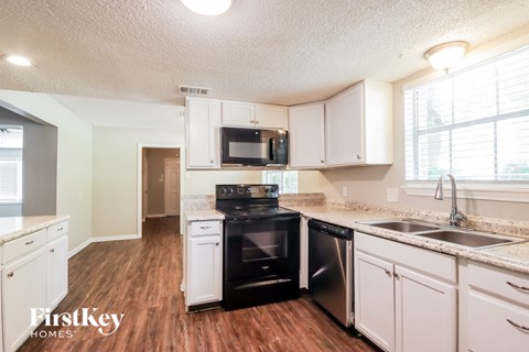 A kitchen with wooden floors and white cabinets.