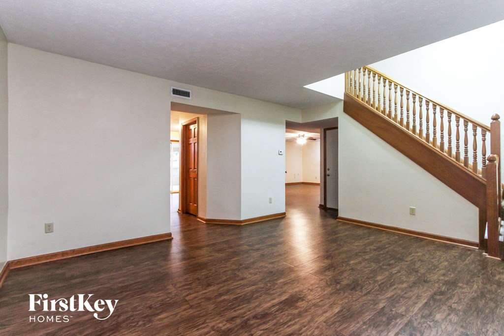 the living room and entryway of an empty house with white walls and wood floors