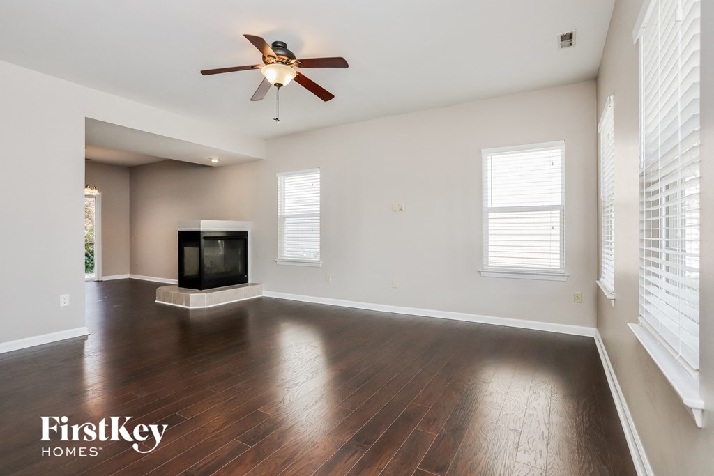 an empty living room with a ceiling fan and a fireplace