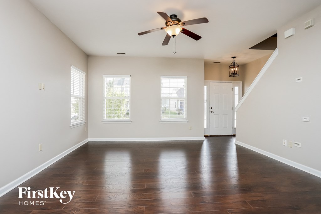 an empty living room with white walls and a ceiling fan
