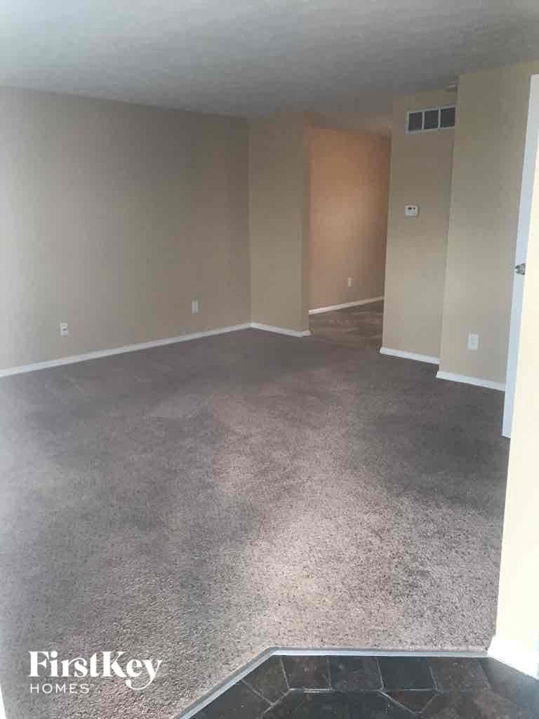 an empty living room with a carpeted floor