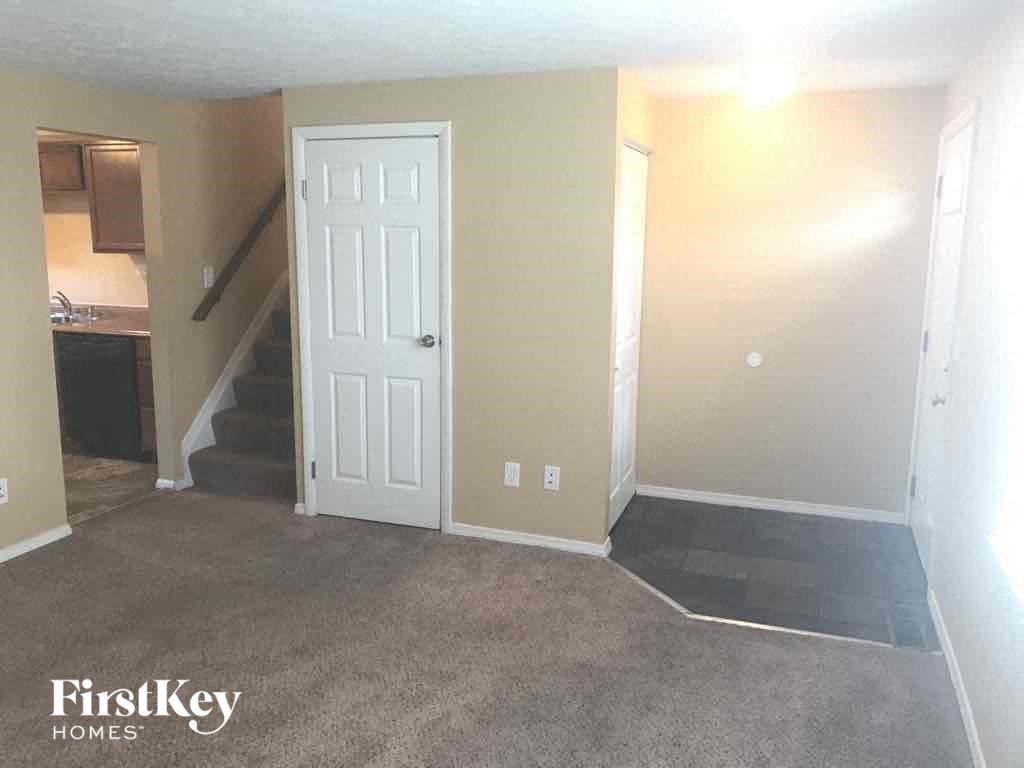 an empty living room with a white door and a staircase