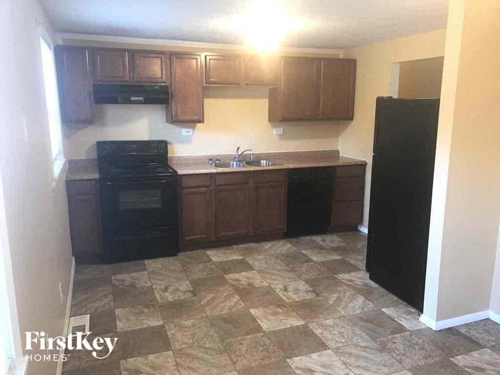 an empty kitchen with black appliances and wooden cabinets