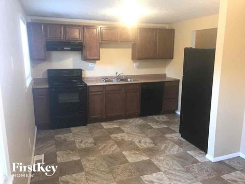 an empty kitchen with black appliances and wooden cabinets