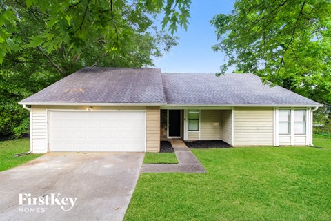 front view of a white house with a driveway and grass