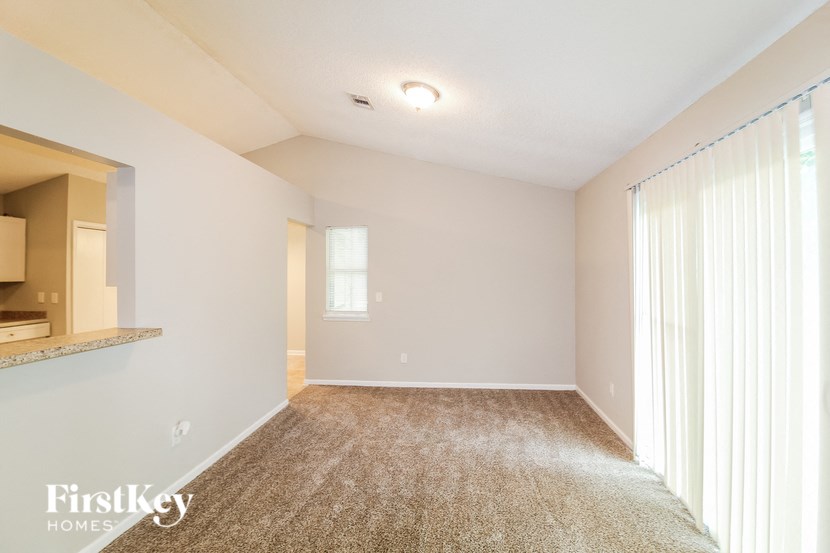 a spacious living room with large windows and carpeting