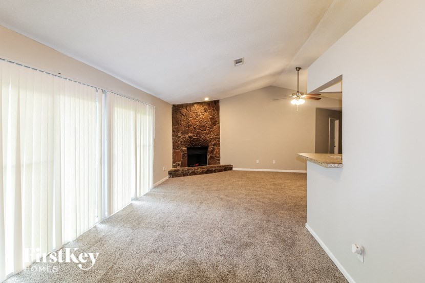 an empty living room with a fireplace and white curtains