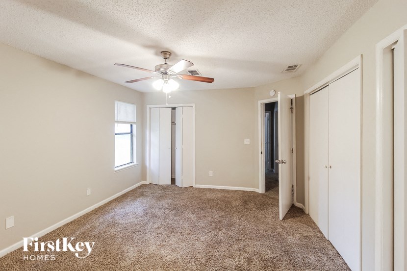 a spacious living room with carpet and a ceiling fan