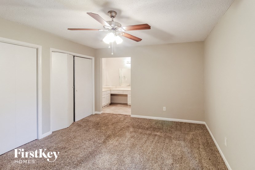 a spacious living room with carpet and a ceiling fan