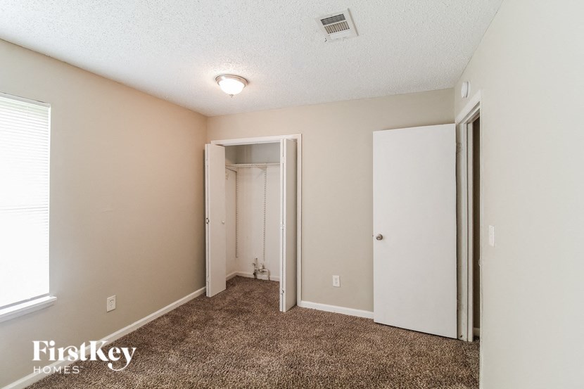 a bedroom with carpet and a closet and a door to a bathroom