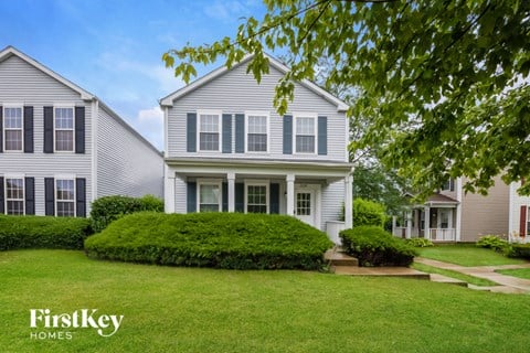 a white house with blue shutters and a green lawn